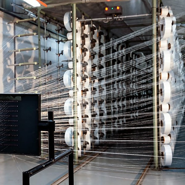 Cords of polymer twine being fed through a weaving loom at the Romatex factory in Cape Town